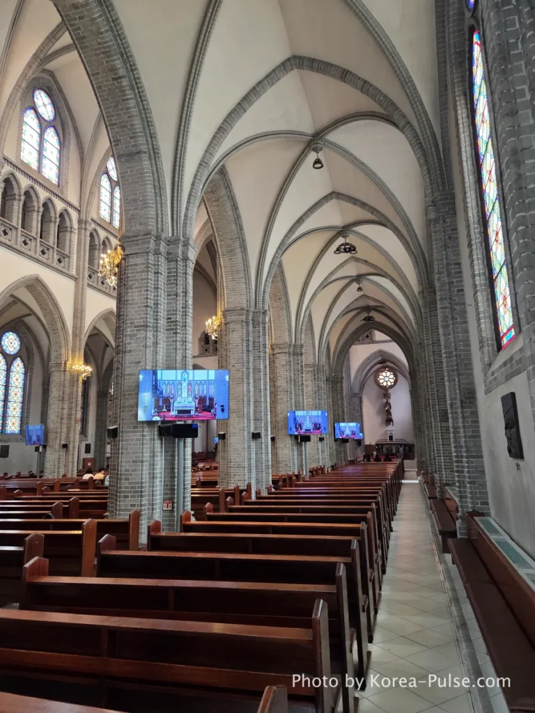Myeongdong Cathedral: Seoul's Gothic Soul, Hidden Above the Shopping District 7 Side aisle of Myeongdong Cathedral interior showing brick composite pillars and pointed Gothic arches