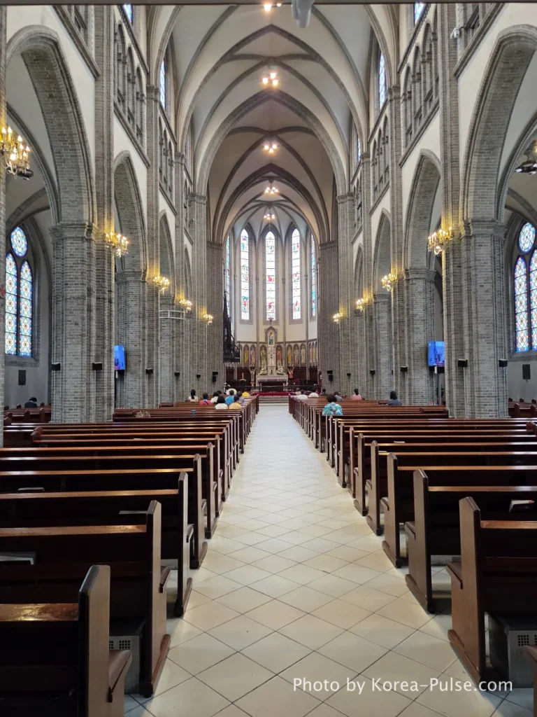 Myeongdong Cathedral: Seoul's Gothic Soul, Hidden Above the Shopping District 6 Interior of Myeongdong Cathedral looking toward the high altar — ribbed Gothic vaulting, wooden pews, pointed arches and brick pillars