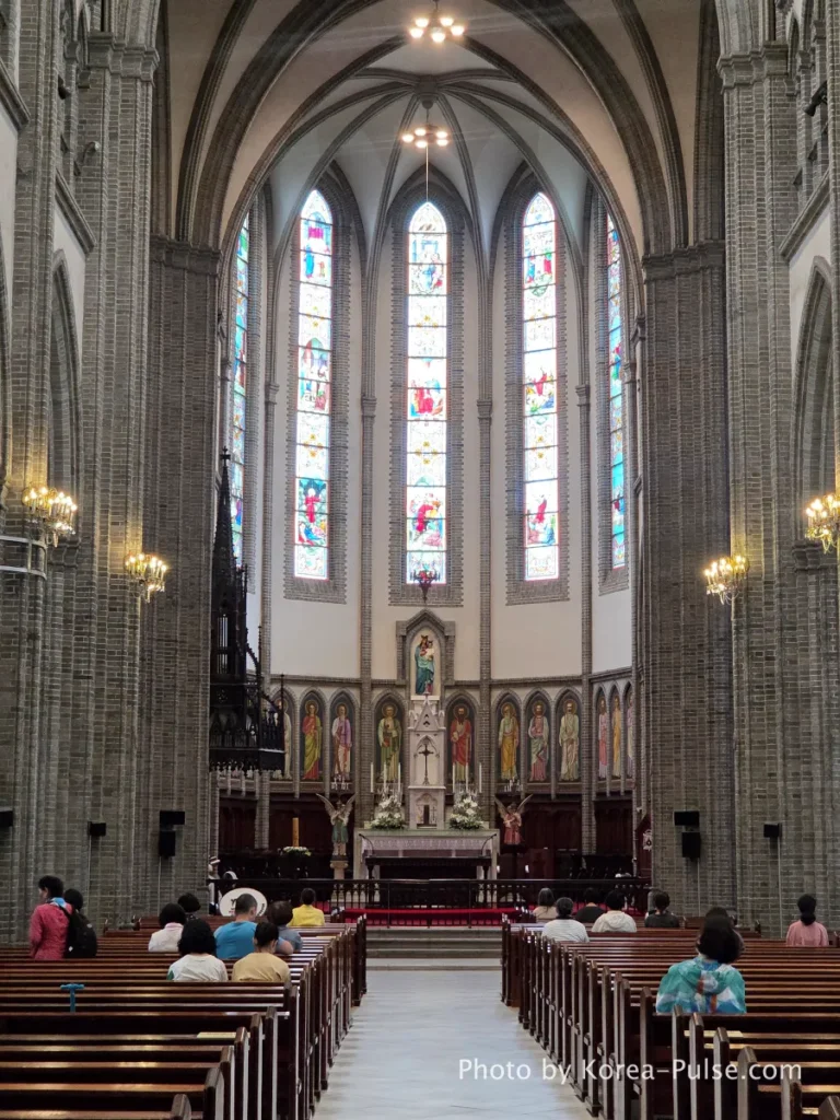 Myeongdong Cathedral: Seoul's Gothic Soul, Hidden Above the Shopping District 8 High altar and sanctuary of Myeongdong Cathedral Seoul with lancet stained glass windows behind — Catholic Gothic Revival interior