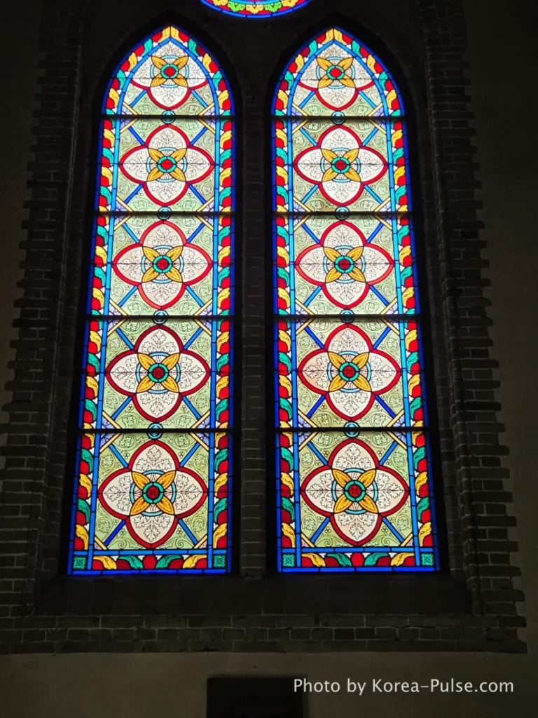 Myeongdong Cathedral: Seoul's Gothic Soul, Hidden Above the Shopping District 11 Close-up detail of colorful stained glass window at Myeongdong Cathedral — geometric and floral designs in rich colours