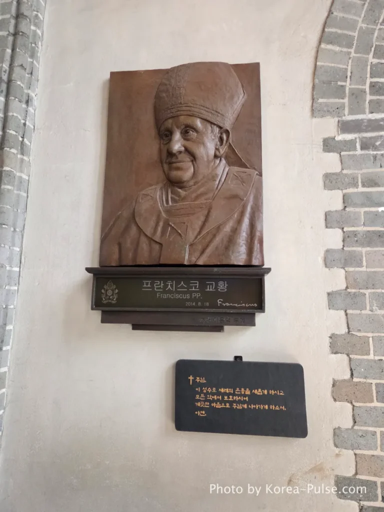 Myeongdong Cathedral: Seoul's Gothic Soul, Hidden Above the Shopping District 12 Bronze relief plaque commemorating Pope Francis mounted inside Myeongdong Cathedral Seoul