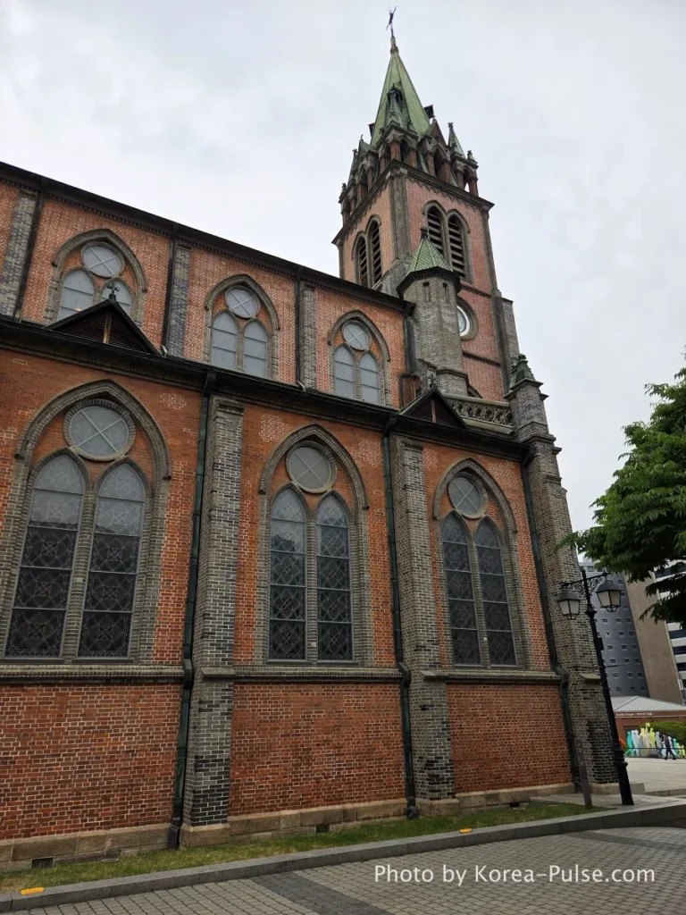 Myeongdong Cathedral: Seoul's Gothic Soul, Hidden Above the Shopping District 13 Side exterior of Myeongdong Cathedral Seoul showing repeating pointed arch windows, brick buttresses and Gothic Revival detailing