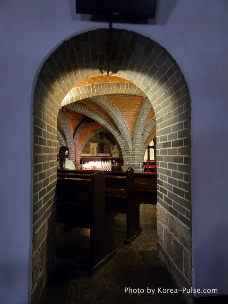 Myeongdong Cathedral: Seoul's Gothic Soul, Hidden Above the Shopping District 15 Arched brick entrance with steps leading down to the underground Crypt Chapel beneath Myeongdong Cathedral Seoul