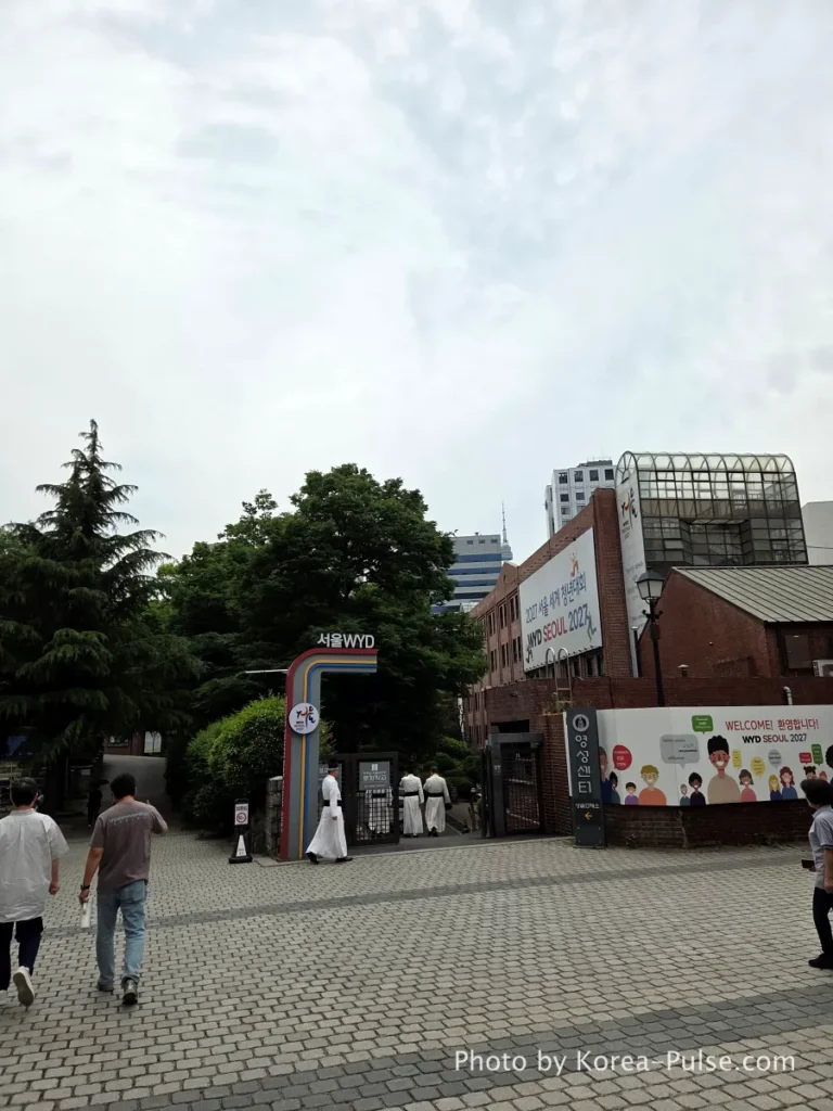 Myeongdong Cathedral: Seoul's Gothic Soul, Hidden Above the Shopping District 19 Three Catholic priests in black cassocks walking across the courtyard plaza of Myeongdong Cathedral Seoul