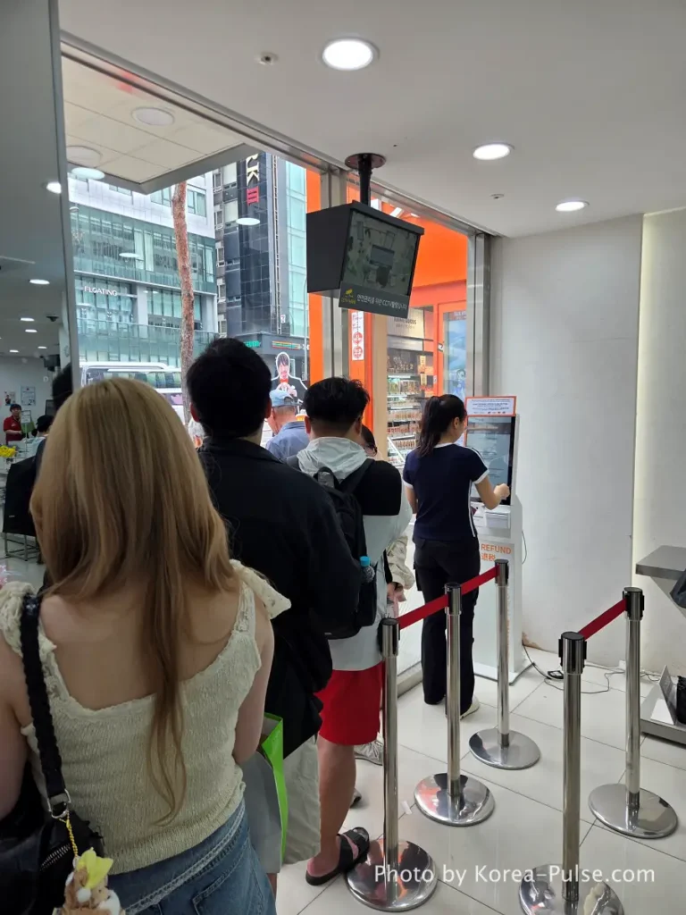International tourists waiting in line at tax refund counter on 1st floor Daiso Myeongdong Station branch Seoul