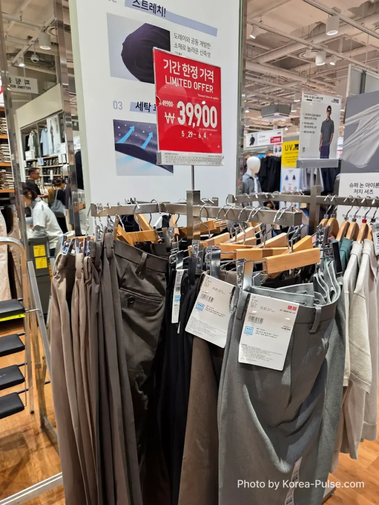 Rack of men's stretch trousers in the Uniqlo Seoul store with a red Limited Offer sign showing the Gamsaje sale price of 39,900 won, reduced from 49,900 won