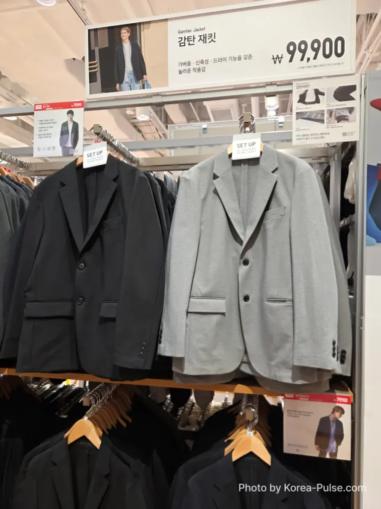 Uniqlo Gamtan Jacket (감탄 재킷) display showing navy and light grey blazers hanging on a rack with a sale price tag of 79,900 won, reduced from 99,900 won