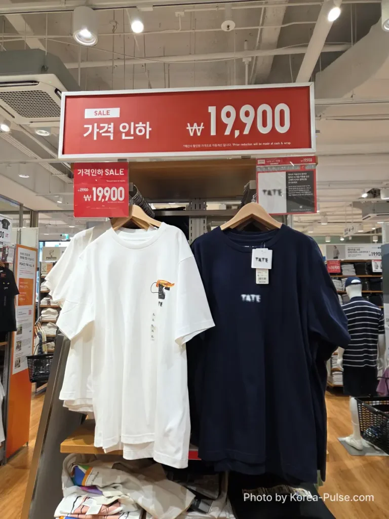 Uniqlo UT graphic t-shirts from the Tate Museum collaboration on display in Seoul, with a red 가격 인하 SALE sign showing the reduced price of 19,900 won