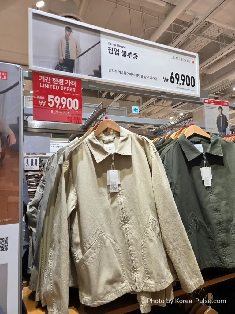 Uniqlo and JW Anderson Zip-up Blouson (집업 블루종) hanging on a rack in beige and olive green colorways, with a red Limited Offer sign showing the Gamsaje sale price of 59,900 won reduced from 69,900 won