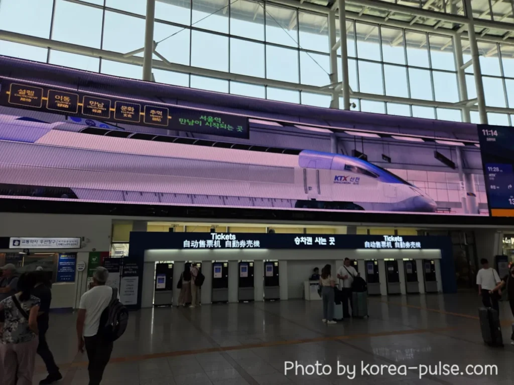 How to Buy a KTX Ticket at Seoul Station: A Friendly Step-by-Step Guide for Foreigners 1 Seoul Station main hall showing the automated KTX ticket machines under the large Tickets sign, with a KTX train displayed on the giant LED screen above