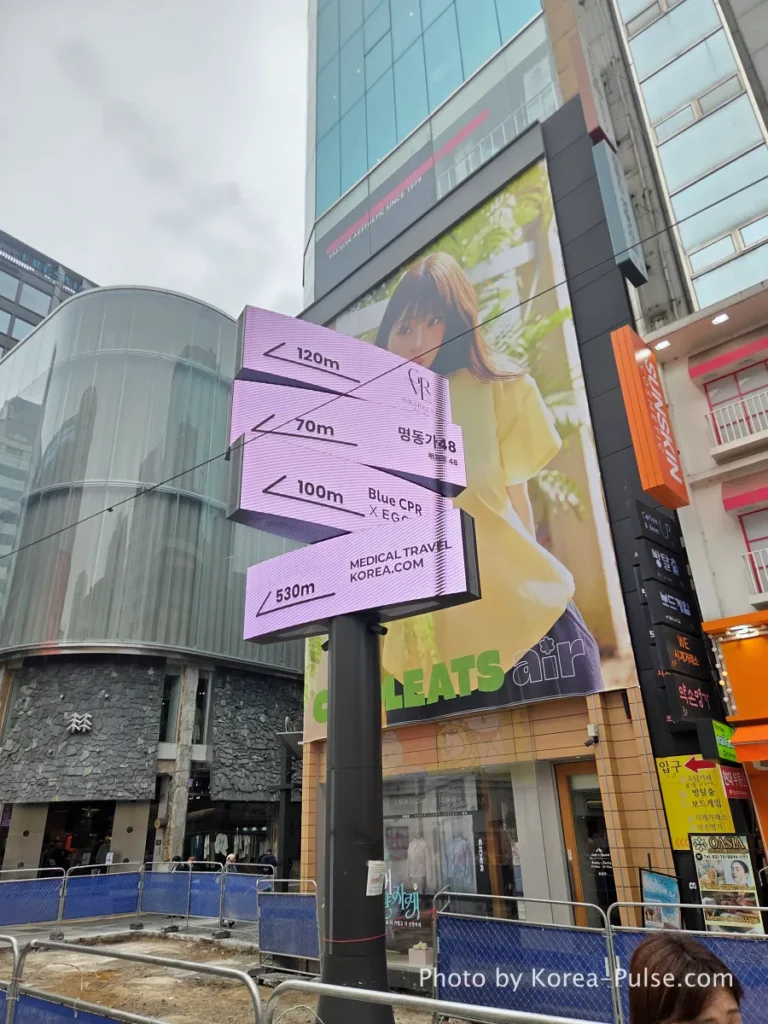 Large new digital wayfinding signage pillar being installed in central Myeongdong street showing directions to nearby landmarks in metres