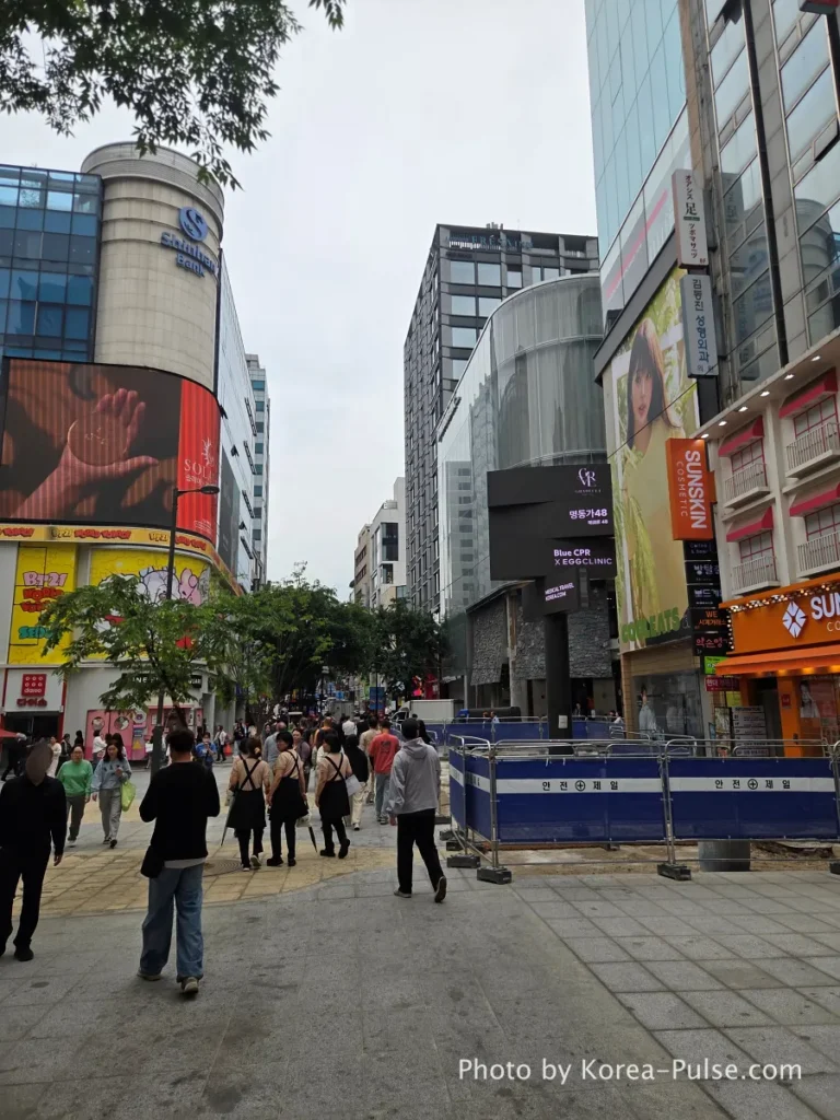 Myeongdong street - main shopping street in May 2026 with crowds of pedestrians, large LED billboard, MLB and brand stores visible