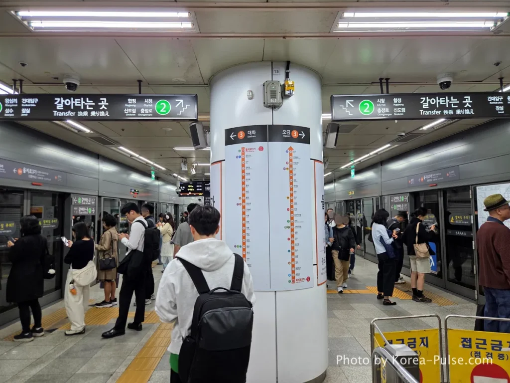 Inside Seoul Rush Hour: Why Korea's Subway System Feels Different 2 Seoul Metro platform with white central pillar showing route maps, passengers waiting on both sides in front of screen doors