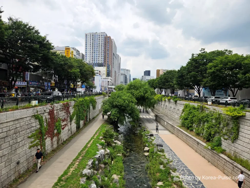 Gwangjang Market Seoul: The Complete Entry Guide — Part 1 2 Cheonggyecheon stream Seoul with tree-lined walkways and stone walls viewed from a footbridge near Gwangjang Market