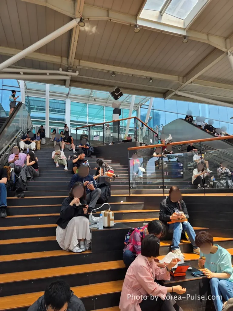 Seoul Station wooden bleacher stairs filled with KTX passengers eating before departure