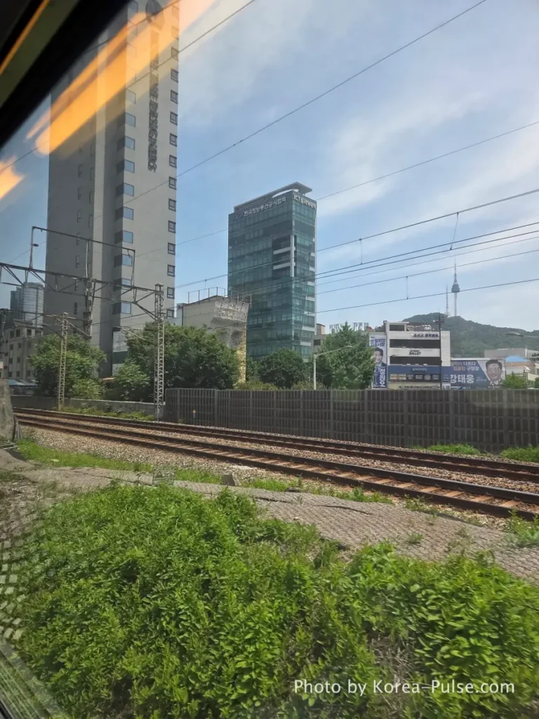 Clear blue sky and green hillside view from KTX window approaching Daegu on Korea rail trip