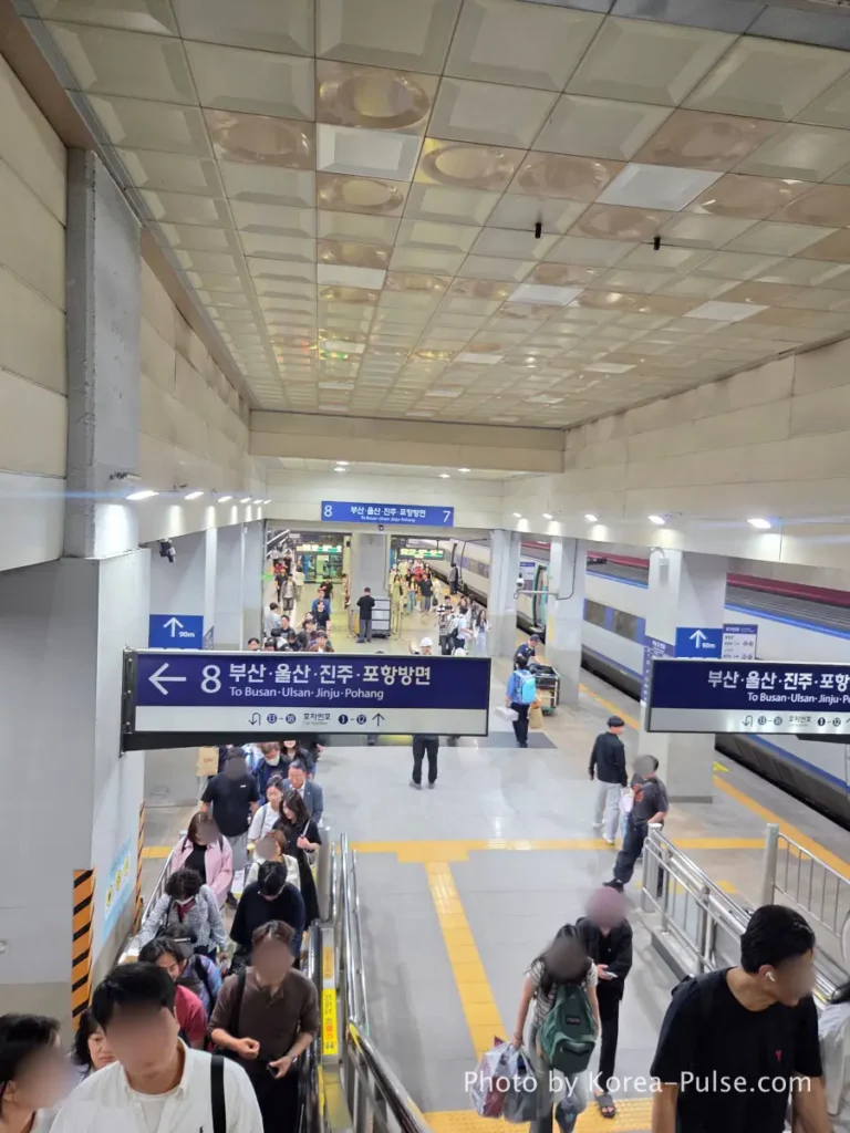Dongdaegu Station lower concourse with passengers and blue directional signs on arrival