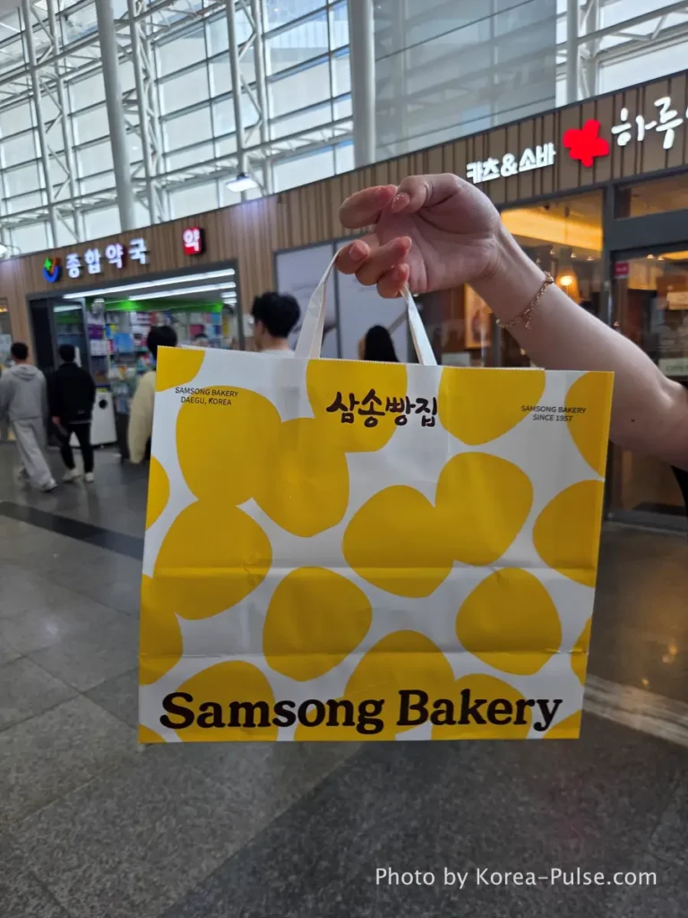 Samsong Bakery yellow shopping bag held up at Dongdaegu Station after KTX family trip Korea