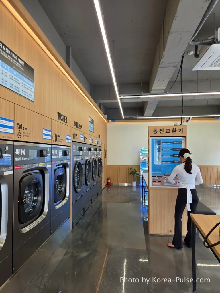 Woman using coin changer machine 동전교환기 at Easy Wash Korean coin laundry to exchange paper bills for 500 won coins needed for sneaker washing station in Seoul