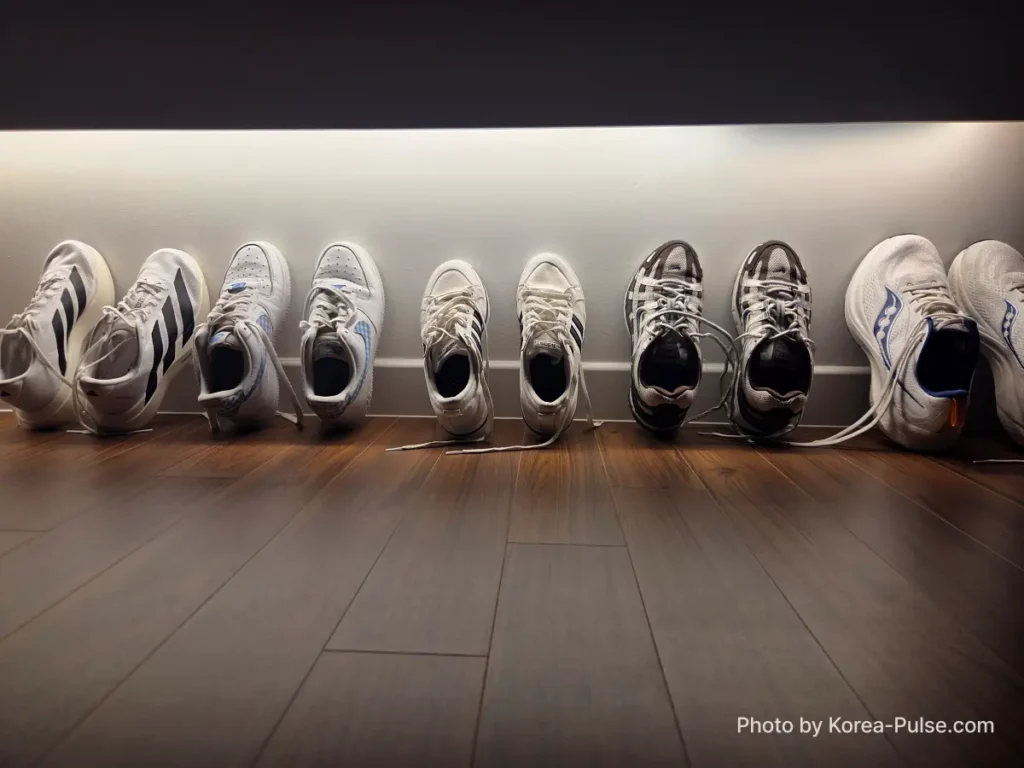 Five pairs of clean sneakers lined up against wall at home after drying at Korean coin laundry 빨래방 Easy Wash Seoul with tongues open to air dry
