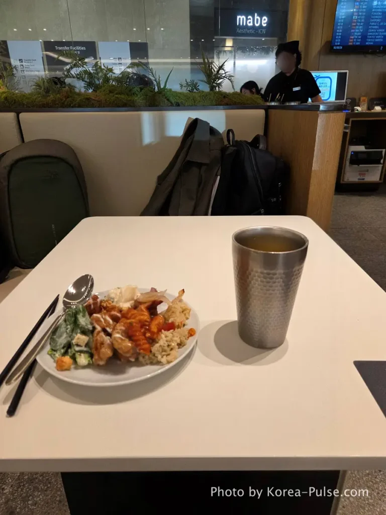 Incheon Airport Smartpass: Skip the Line & Hit the Lounge Fast 14 Plate of lounge food and glass of fruit juice at SKYHUB Lounge table Incheon Airport departure