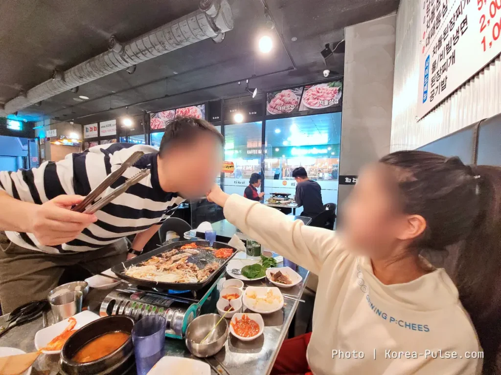 K-BBQ Etiquette Without the Anxiety: How to Grill, Share, and Read the Table Like a Local 5 Family sharing food across a Korean barbecue table