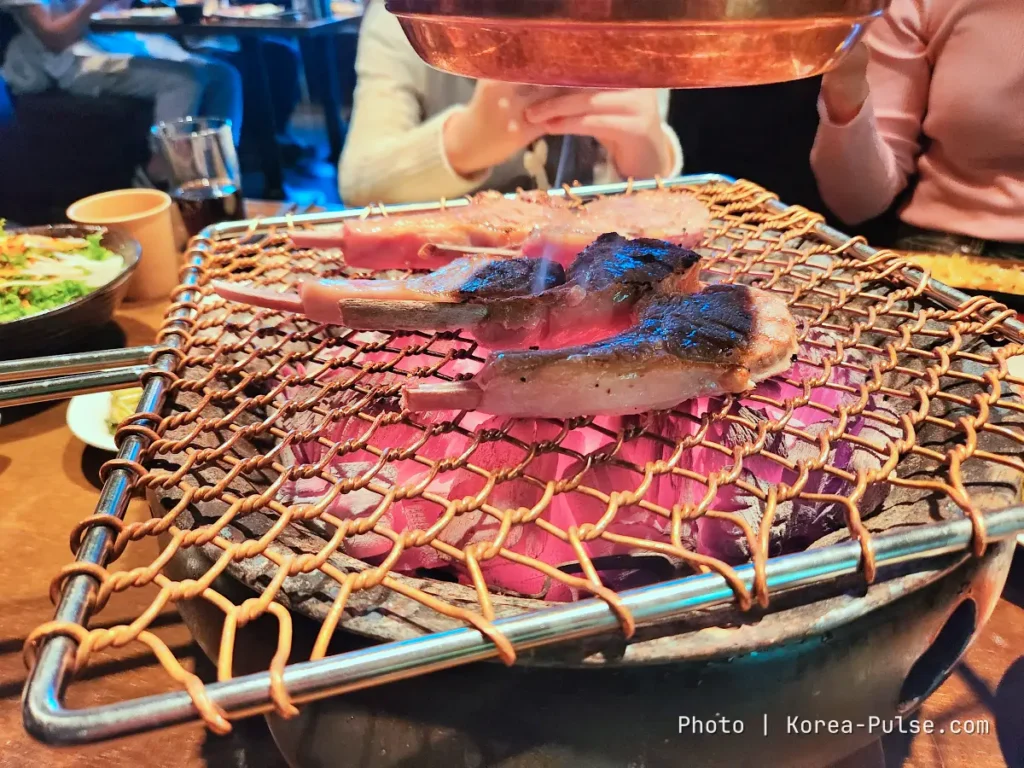 K-BBQ Etiquette Without the Anxiety: How to Grill, Share, and Read the Table Like a Local 4 Thick lamb chops searing over charcoal at a Korean barbecue restaurant