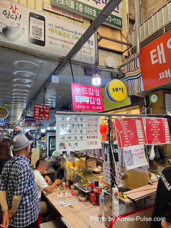 Tourists and locals dining at wholesale corridor stall Gwangjang Market
