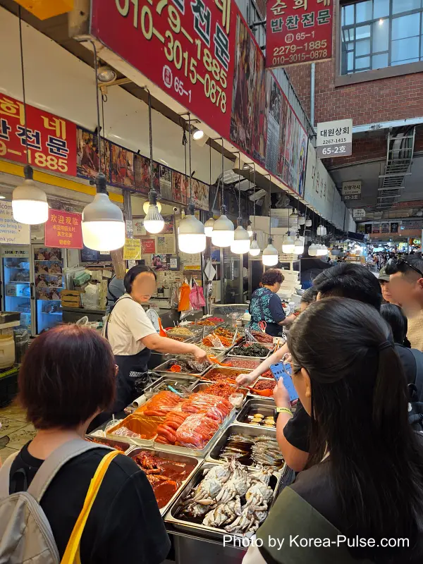 Foreign tourists browsing banchan stall at Gwangjang Market Seoul
