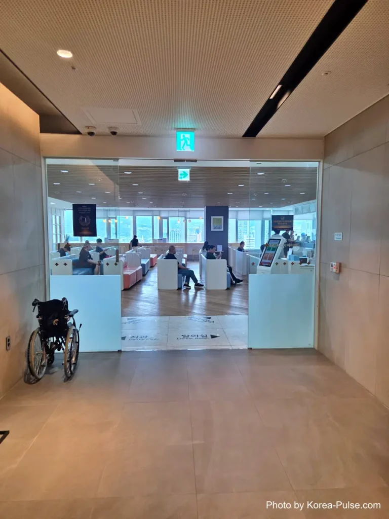 Minimalist elevator lobby with a wheelchair-accessibility symbol on the floor, leading to a Korean health checkup center