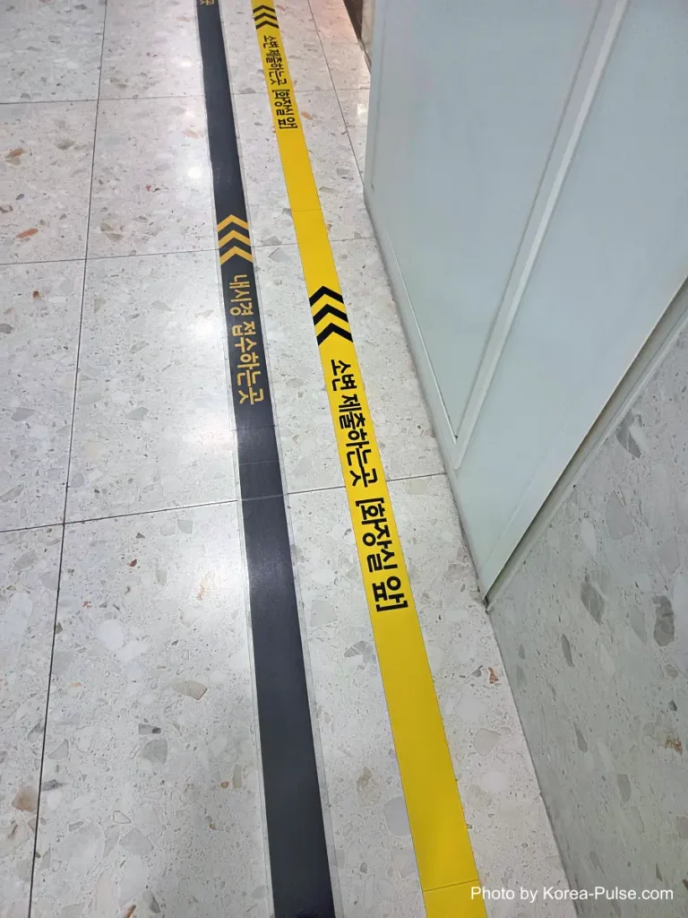 Yellow directional arrows taped on the floor of a hospital corridor
