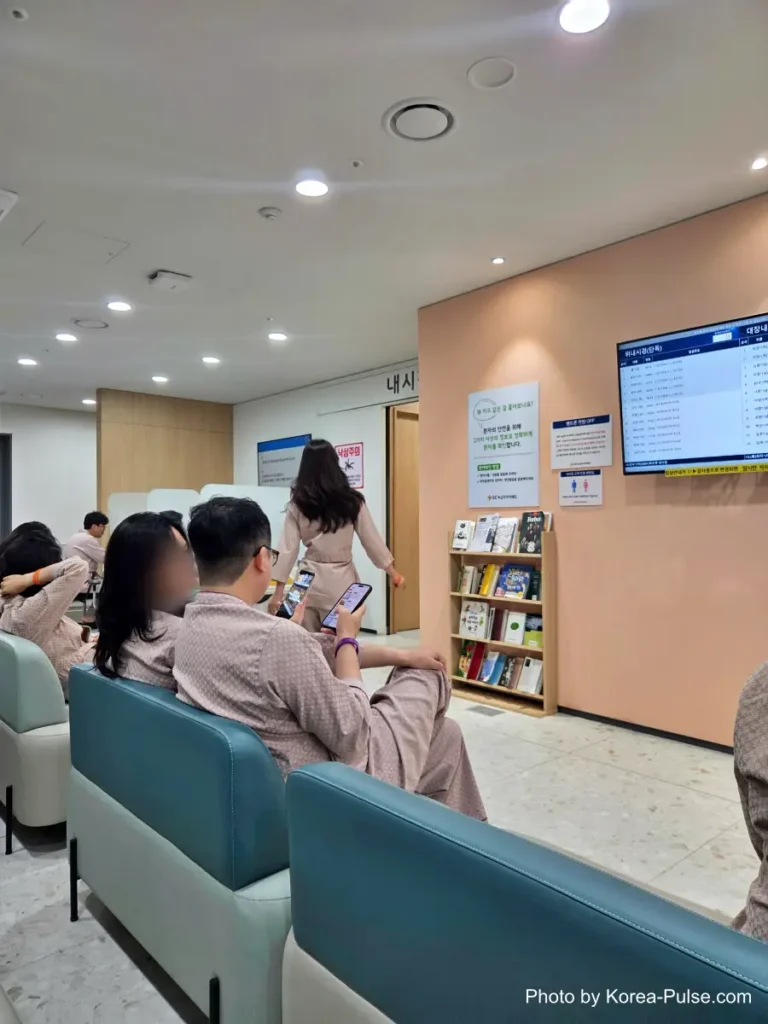 Patients in hospital gowns seated in a waiting room outside the endoscopy department