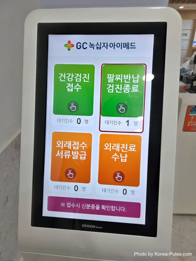 Kiosk screen with green and orange buttons for returning a health checkup wristband and finishing the visit