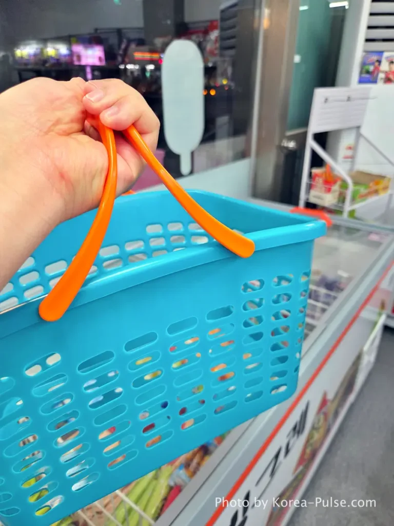 Unmanned Ice Cream Store Korea: Stunning 314% Retail Boom (2026) 4 📁 20260716_222026.webp · ALT: Hand holding a blue shopping basket inside an unmanned ice cream store